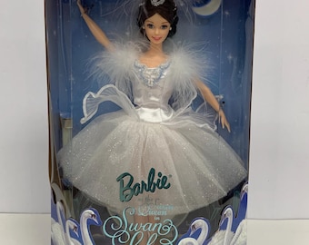 Op de afbeelding: Collector Edition Barbie-pop in een doorzichtige display case. De pop draagt een wit balletkostuum met een gevederde sjaal en een tiara. De verpakking toont de tekst "Barbie as the Swan Queen in Swan Lake" en zwanenillustraties.