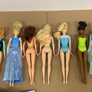K&ouml;nnte beinhalten: Sechs Modepuppen mit verschiedenen Frisuren und Outfits. Die Puppen haben unterschiedliche Hautt&ouml;ne und tragen Badeanz&uuml;ge oder Kleider in Schwarz, Blau und Gr&uuml;n. Einige Puppen haben lange Haare, andere sind hochgesteckt.