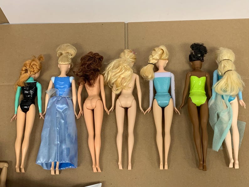 K&ouml;nnte beinhalten: Sechs Modepuppen mit verschiedenen Frisuren und Outfits. Die Puppen haben unterschiedliche Hautt&ouml;ne und tragen Badeanz&uuml;ge oder Kleider in Schwarz, Blau und Gr&uuml;n. Einige Puppen haben lange Haare, andere sind hochgesteckt.