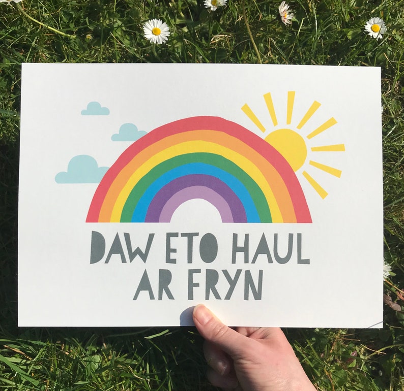 May include: A white card with a rainbow and a sun, with the text "Daw eto haul ar fryn" in gray.