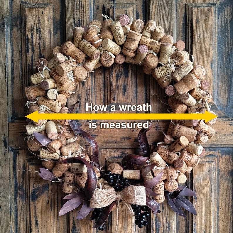 May include: A brown cork wreath with a burlap bow and black berries. The wreath is decorated with dried leaves and is approximately 18 inches in diameter. "How a wreath is measured" is written in yellow text across the center of the wreath.