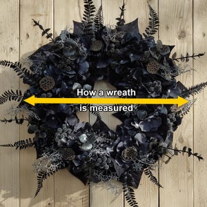 May include: A black and silver wreath with a yellow label that reads "How a wreath is measured".