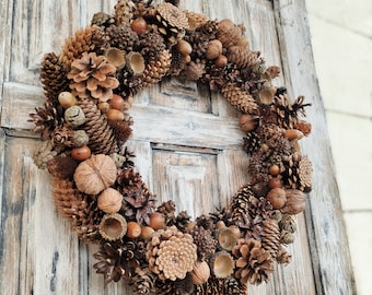 May include: A brown and beige autumnal wreath made of pinecones, acorns, and other natural elements.