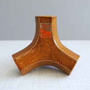 Könnte beinhalten: Ein brauner Kerzenhalter aus Keramik mit dreieckiger Basis und einem Etikett mit der Aufschrift "Made in Italy".