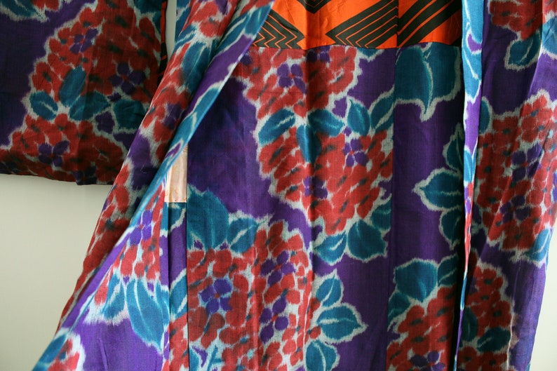 Op de afbeelding: Een paarse en turquoise kimono met een bloemenpatroon. De kimono is gemaakt van een zachte, zijdeachtige stof en heeft een traditioneel Japans ontwerp.