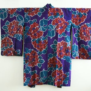 Op de afbeelding: Een paarse kimono met een bloemenpatroon in tinten rood en blauw. De kimono is gemaakt van een zachte, lichte stof en heeft een traditioneel Japans ontwerp.