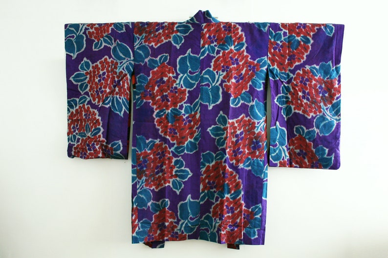 Op de afbeelding: Een paarse kimono met een bloemenpatroon in tinten rood en blauw. De kimono is gemaakt van een zachte, lichte stof en heeft een traditioneel Japans ontwerp.