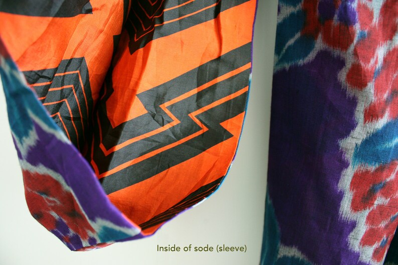 Op de afbeelding: De binnenkant van een traditioneel Japans kledingstuk, genaamd "sode", met een feloranje stof met een zwart geometrisch patroon. De stof is dubbelgevouwen en de buitenkant van het kledingstuk is een paars-blauw tie-dye patroon. De tekst "Inside of sode (sleeve)" is zichtbaar onderaan de afbeelding.