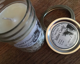 May include: A hand-poured tallow candle in a clear glass jar with a silver lid. The jar has a white label that says "Hand Poured Tallow Candle". The lid has a silver label that says "Meadow Blossom Goods Hand-Poured Tallow Candle Unscented, Beef Tallow, Jar Candle Batch no. 1".