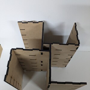 May include: A wooden box with four sides, each side has a black border and is made of plywood. The box is assembled in a way that creates a square shape with an open center.