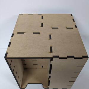 May include: A wooden box with a brown finish and black edges. The box has a series of slots cut into the sides and top.