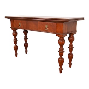 May include: A wooden console table with two drawers and turned legs. The table has a rich brown finish and brass hardware.
