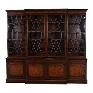 May include: A large, dark wood bookcase with glass-paned doors and diamond-shaped mullions. The lower section features paneled doors with a rich, reddish-brown finish. The bookcase has a classic, traditional design, suitable for displaying books and decor.