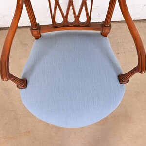 May include: A wooden chair with a light blue fabric seat and a carved back. The chair has a traditional design with fluted legs and a curved back.
