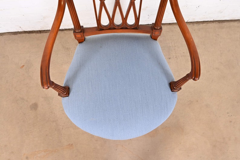 May include: A wooden chair with a light blue fabric seat and a carved back. The chair has a traditional design with fluted legs and a curved back.