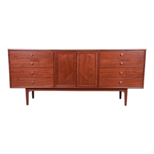 May include: A long, rectangular, wooden dresser with six drawers on each side and two cabinet doors in the center. The dresser has a rich, reddish-brown finish and silver-toned drawer pulls.