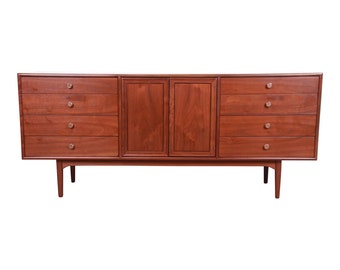May include: A long, rectangular, wooden dresser with six drawers on each side and two cabinet doors in the center. The dresser has a rich, reddish-brown finish and silver-toned drawer pulls.