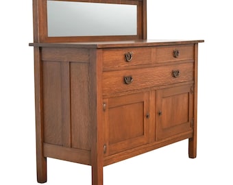May include: A wooden dresser with a rectangular mirror, featuring two drawers and two cabinet doors. The dresser is made of oak and has a warm, brown finish. The hardware is a dark metal. The style is vintage.