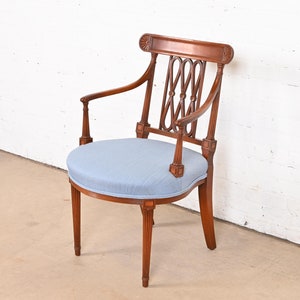 May include: A wooden armchair with a light blue upholstered seat and a decorative back. The chair has a round seat and a curved back with a lattice design.