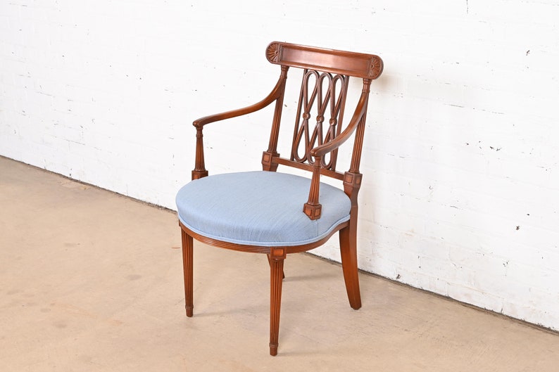 May include: A wooden armchair with a light blue upholstered seat and a decorative back. The chair has a round seat and a curved back with a lattice design.