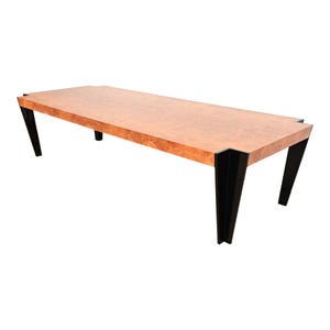 May include: A long, rectangular dining table with a wood top and black metal legs. The table top has a natural wood grain pattern.