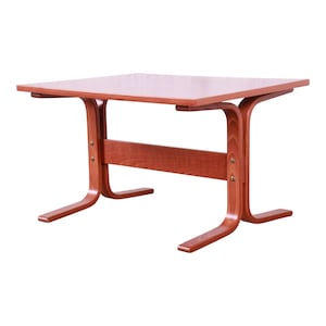 May include: A wooden table with a rectangular top and a unique, curved, wooden base. The table is made of a reddish-brown wood.