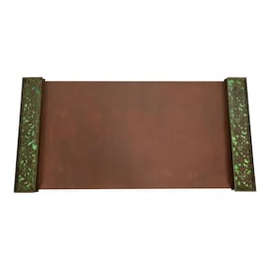 May include: A rectangular desk blotter with a reddish-brown surface. The ends feature ornate, dark green metalwork with a floral design, set against a lighter green background. The blotter is a decorative office accessory.