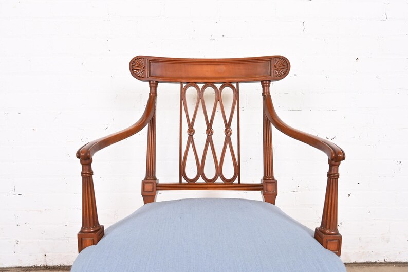 May include: A wooden armchair with a light blue cushion. The chair has a carved back and arms, and a woven design on the back.