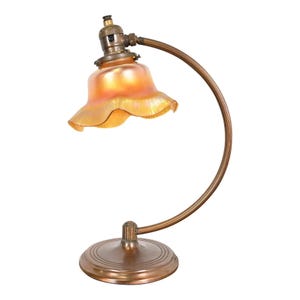May include: A vintage brass desk lamp with a curved arm and a ruffled iridescent glass shade.
