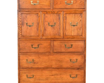 Puede incluir: Un alto aparador de madera con un acabado marrón cálido. Tiene dos cajones en la parte superior, tres puertas en el medio y cuatro cajones en la parte inferior. Los cajones tienen tiradores de latón.