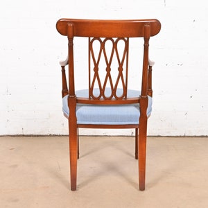 May include: A wooden armchair with a light blue fabric seat and a decorative back with a woven design. The chair has a rounded back and four legs.