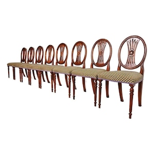 May include: A set of eight antique wooden chairs with a shared seat. The chairs have a dark brown finish, oval backs with carved details, and checkered fabric seats. The legs are slender and slightly curved.