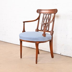 May include: A wooden armchair with a light blue upholstered seat and a carved back. The chair has a rounded seat and a curved back with a decorative design.
