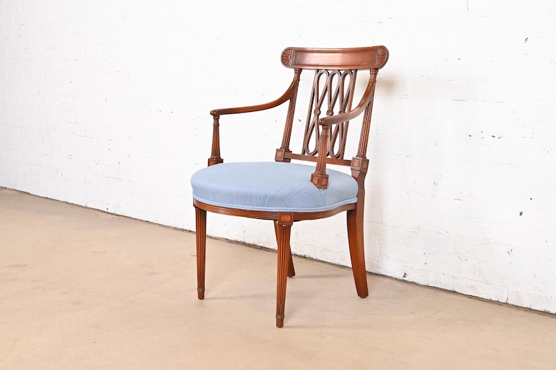 May include: A wooden armchair with a light blue upholstered seat and a carved back. The chair has a rounded seat and a curved back with a decorative design.