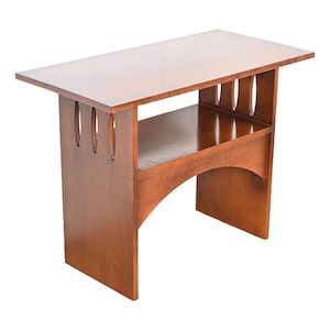 May include: A wooden end table with a lower shelf and an arched opening in the front. The table has a dark brown stain and intricate cutouts on the sides.