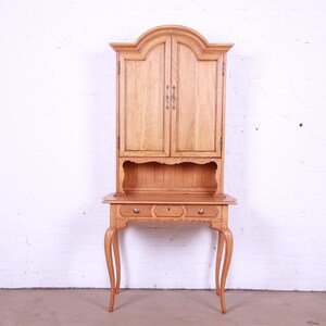 May include: A light wood desk with a hutch. The desk has three drawers and cabriole legs. The hutch has two doors and a shelf.