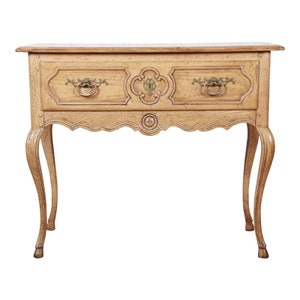 May include: A light wood console table with a single drawer and ornate carvings. The table has cabriole legs and a scalloped apron.