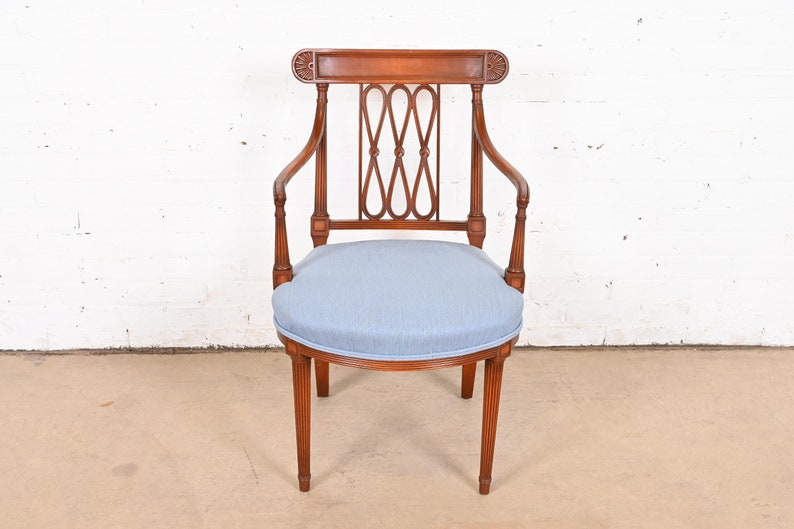 May include: A wooden armchair with a light blue upholstered seat and a carved back.