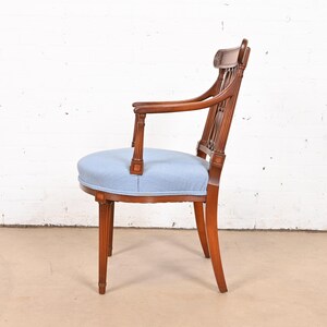 May include: A wooden armchair with a light blue upholstered seat and back. The chair has a carved design on the back and arms.