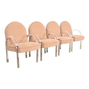 May include: Four beige upholstered chairs with clear acrylic frames and arms. The chairs are arranged in a row.