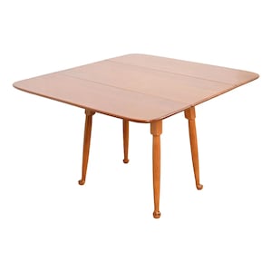 May include: A wooden folding table with a light brown finish and four turned legs. The table has a simple, classic design.