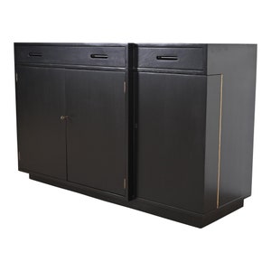 May include: A black wooden sideboard with two doors and two drawers. The sideboard has a gold trim along the edges.
