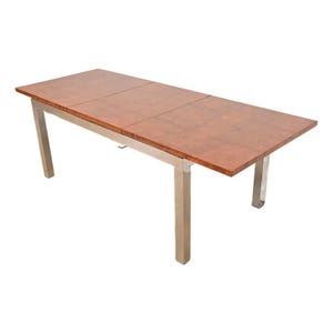 May include: A rectangular dining table with a reddish-brown wood top and silver metal legs. The table has a three-panel design on the tabletop. The legs are square and provide a sturdy base for the table.