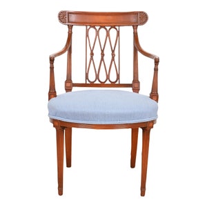 May include: A wooden armchair with a light blue fabric seat and a carved back. The chair has a rounded back and fluted legs.