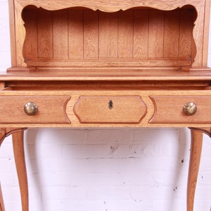 May include: A wooden cabinet with a single drawer and a shelf. The cabinet has cabriole legs and a light wood finish.
