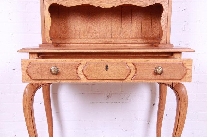 May include: A wooden cabinet with a single drawer and a shelf. The cabinet has cabriole legs and a light wood finish.