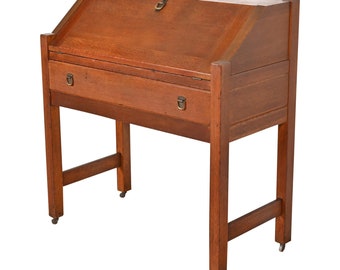 Puede incluir: Un escritorio de madera con un frente abatible y un solo cajón. El escritorio tiene un acabado marrón oscuro y está soportado por cuatro patas con una viga transversal.