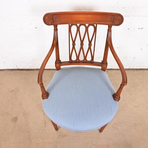 May include: A wooden chair with a light blue upholstered seat and a carved back. The chair has a traditional design with a curved back and arms.