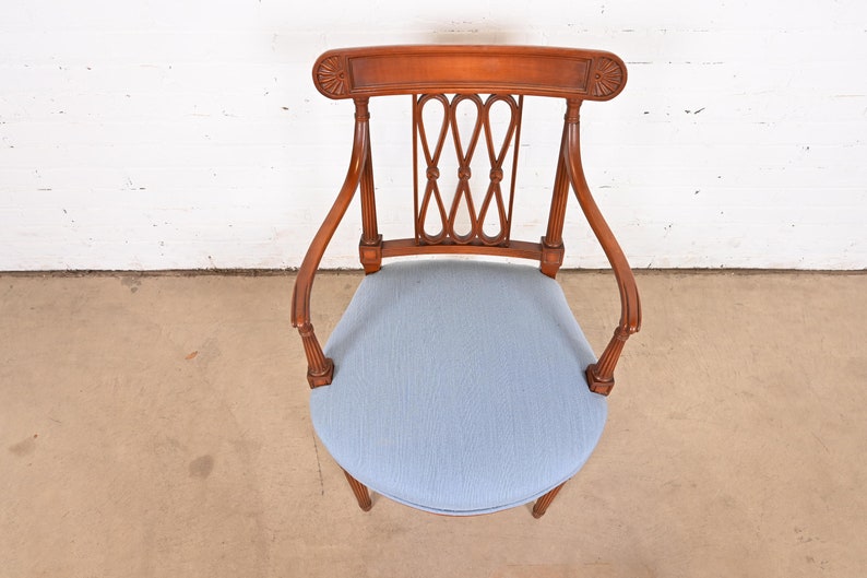 May include: A wooden chair with a light blue upholstered seat and a carved back. The chair has a traditional design with a curved back and arms.