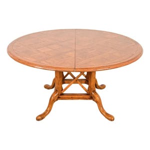 May include: A round wooden dining table with a light brown finish. The tabletop has a parquet pattern. The table has four curved legs and a supporting structure. The table is approximately 48 inches in diameter.